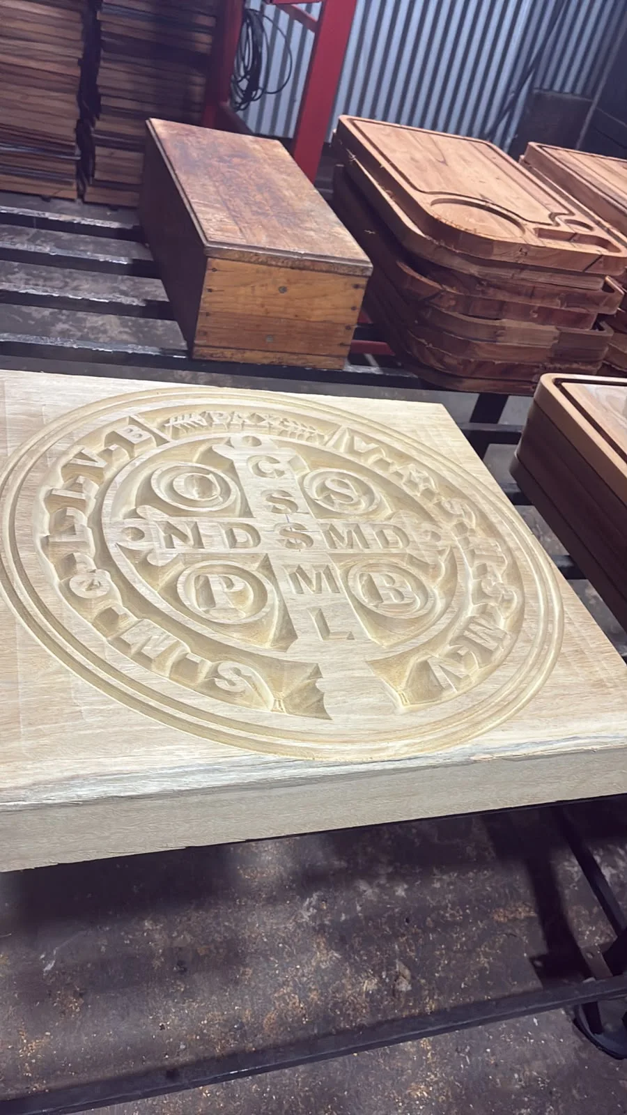 Medalha de São Bento esculpida em relevo na madeira, ainda na mesa da máquina